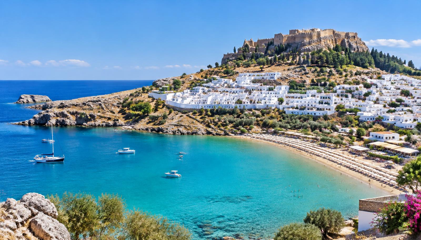Lindos på Rhodos med vita hus nedanför akropolis och turkos vik